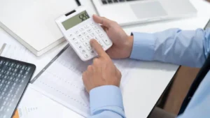 Accountant using a white calculator to estimate payroll for a local firm in Witney